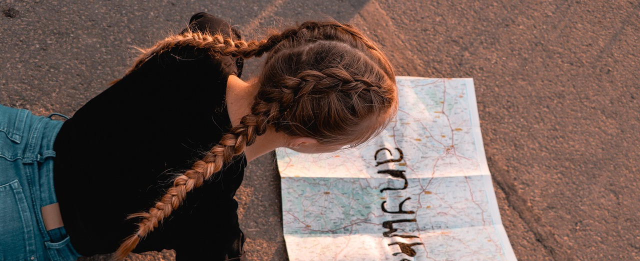 A girl reading a map while comfortably lying on the road